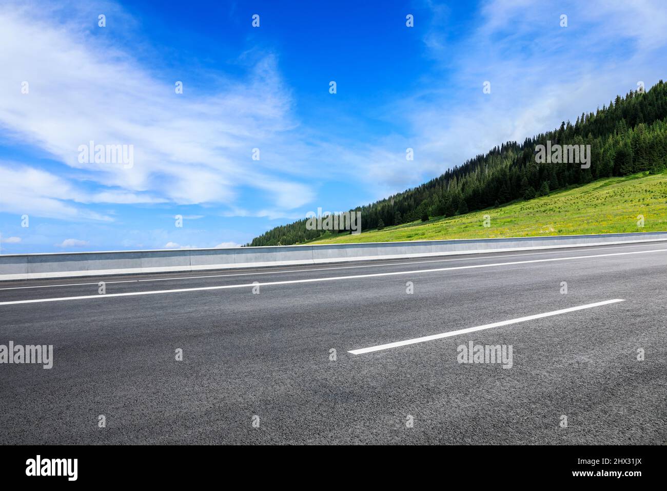 Asphaltstraße und Berglandschaft unter blauem Himmel Stockfoto
