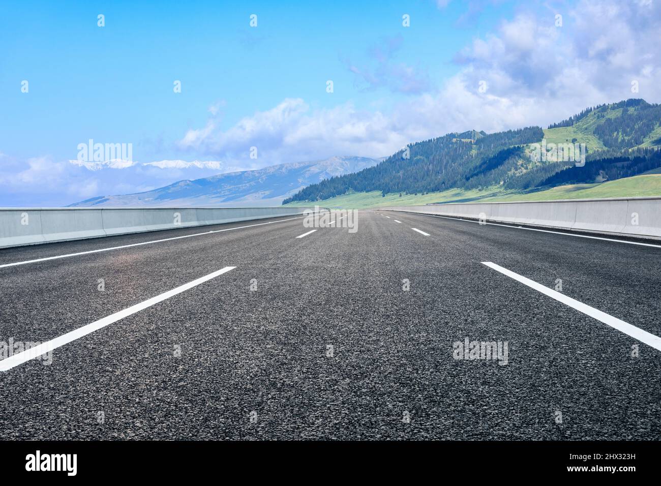 Asphaltstraße und Berglandschaft unter blauem Himmel Stockfoto
