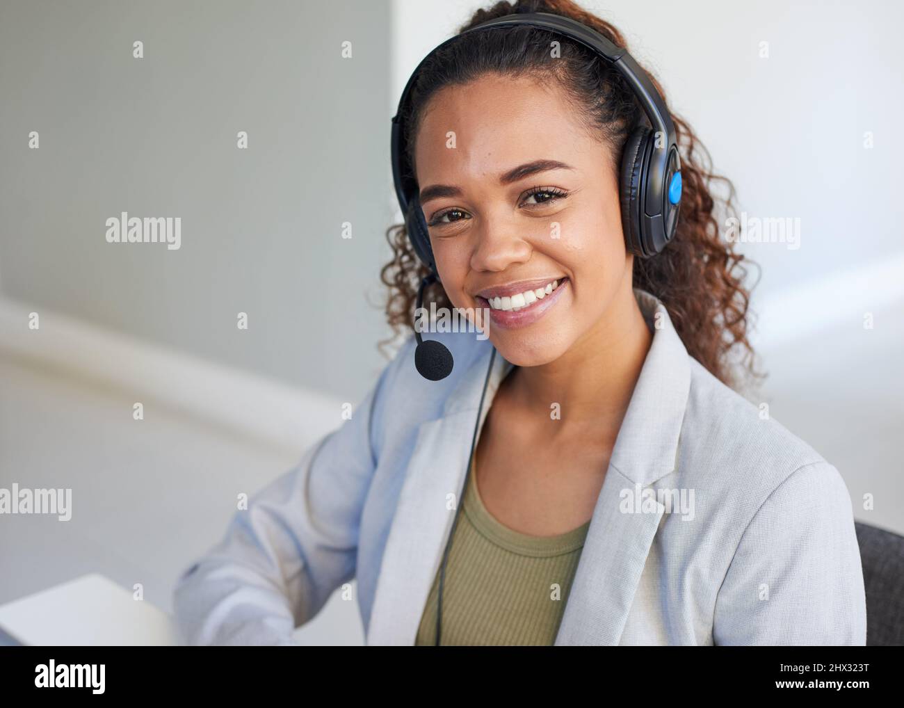 Eine junge Frau lächelt zur Kamera, die einen Kopfhörer mit Mikrofon trägt Stockfoto