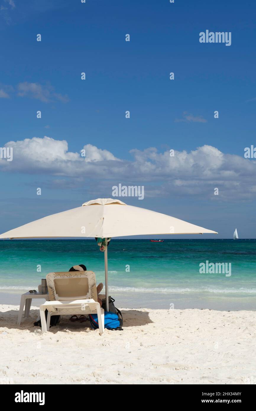 Rückansicht eines Touristen, der auf einer Sonnenliege am Strand vor dem klaren blauen Himmel in Mexiko sitzt Stockfoto