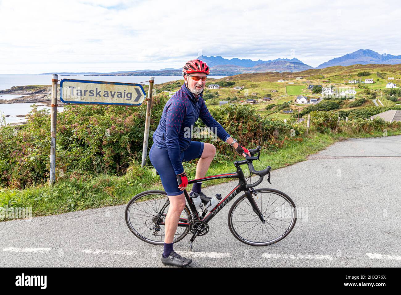 Ein Radfahrer im Dorf Tarskavaig in der Tarskavaig Bay auf dem Sleat Penisula im Süden der Isle of Skye, Highland, Schottland, Großbritannien. Die Cuillins A Stockfoto