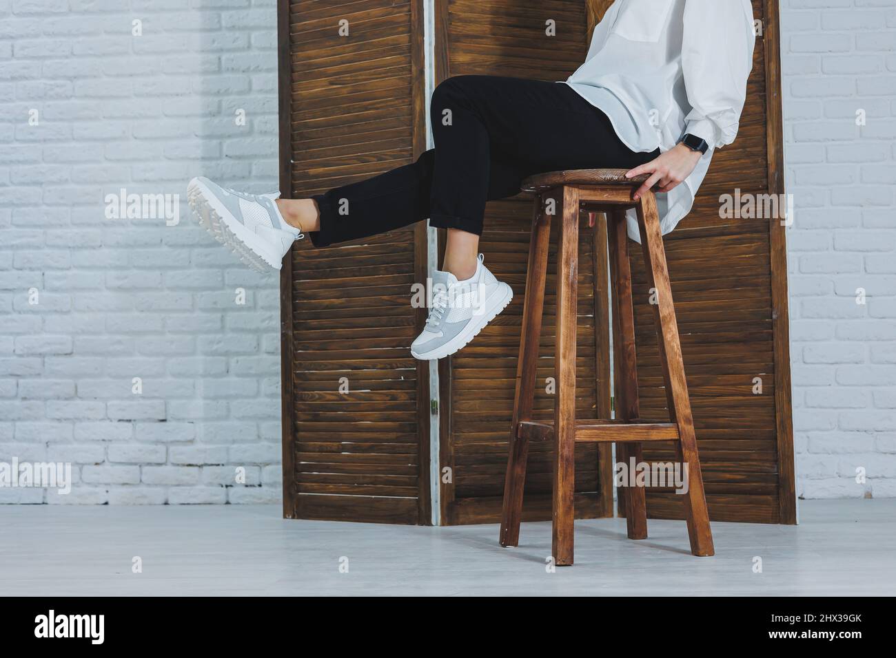 Nahaufnahme der weiblichen Beine in schwarzer Jeans in modischen weißen Leder-Sneakers. Modische Frau in neuen Sneakers. Moderne, saisonale Kollektion von stylischem sne Stockfoto