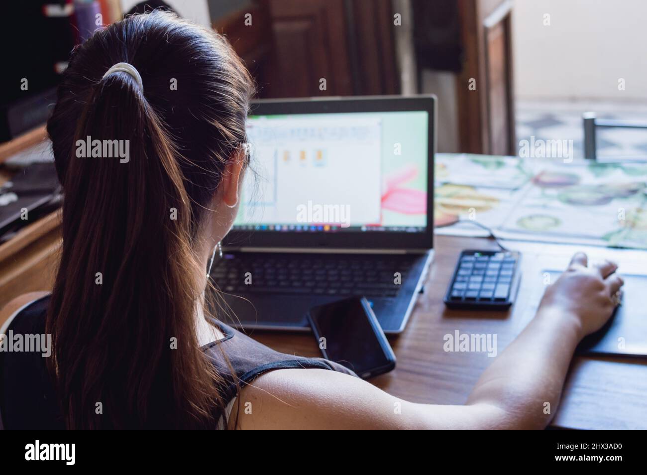 Unternehmungslustige junge Frau, die online mit ihrem Computer in ihrem Heimbüro arbeitet, Kopierraum. Stockfoto