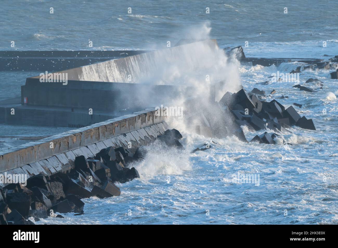 Im Hafen der Insel Helgoland, Nordsee, treffen große Wellen auf Betonwände. Windiger Wintertag im deutschen Archipel. Stockfoto