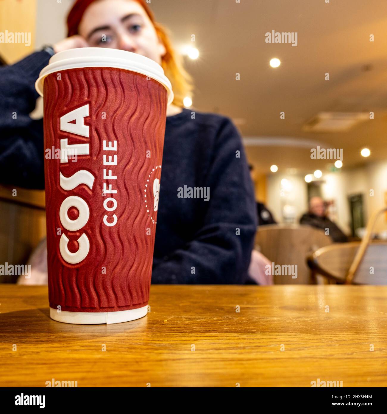 Epsom Surrey London, 9 2022. März, Junge nachdenkliche Frau, die im Costa Coffee Shop sitzt Stockfoto