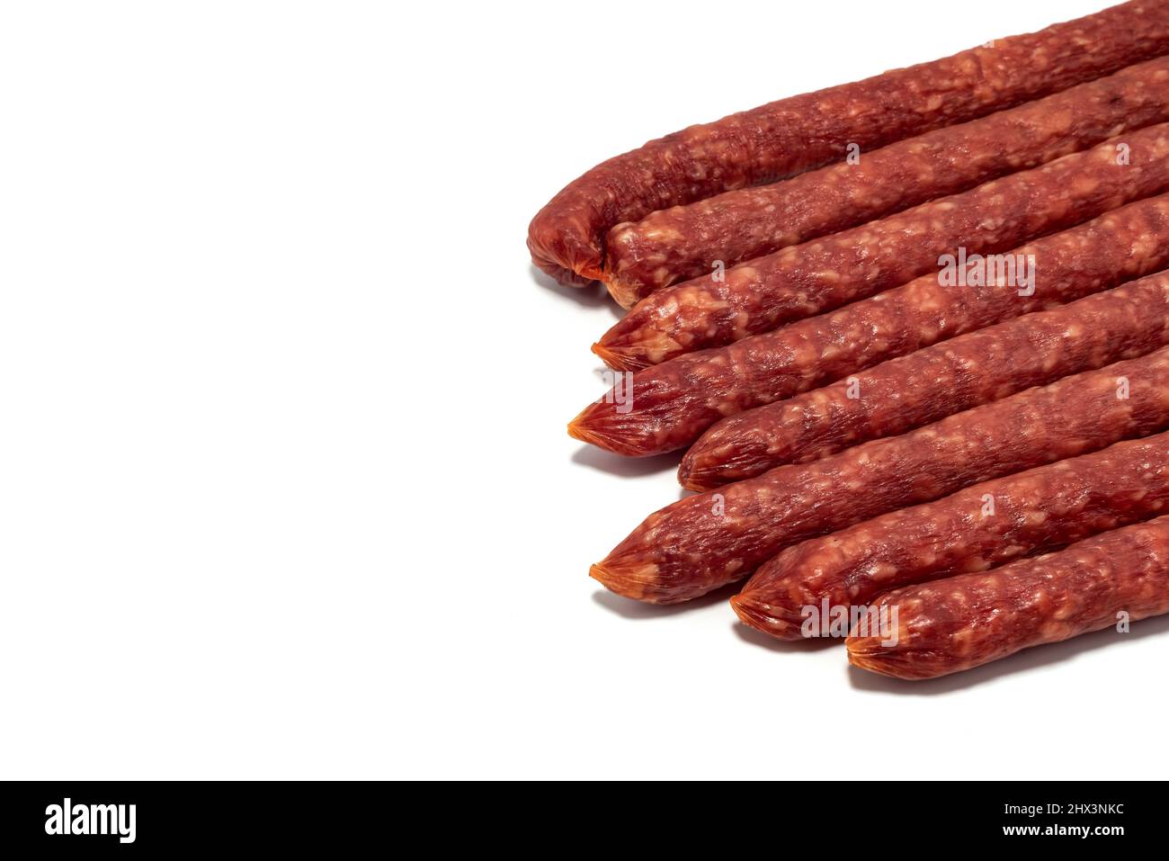 Trockene Wurst auf weißem Hintergrund. Dünne Räucherwürste isoliert Stockfoto