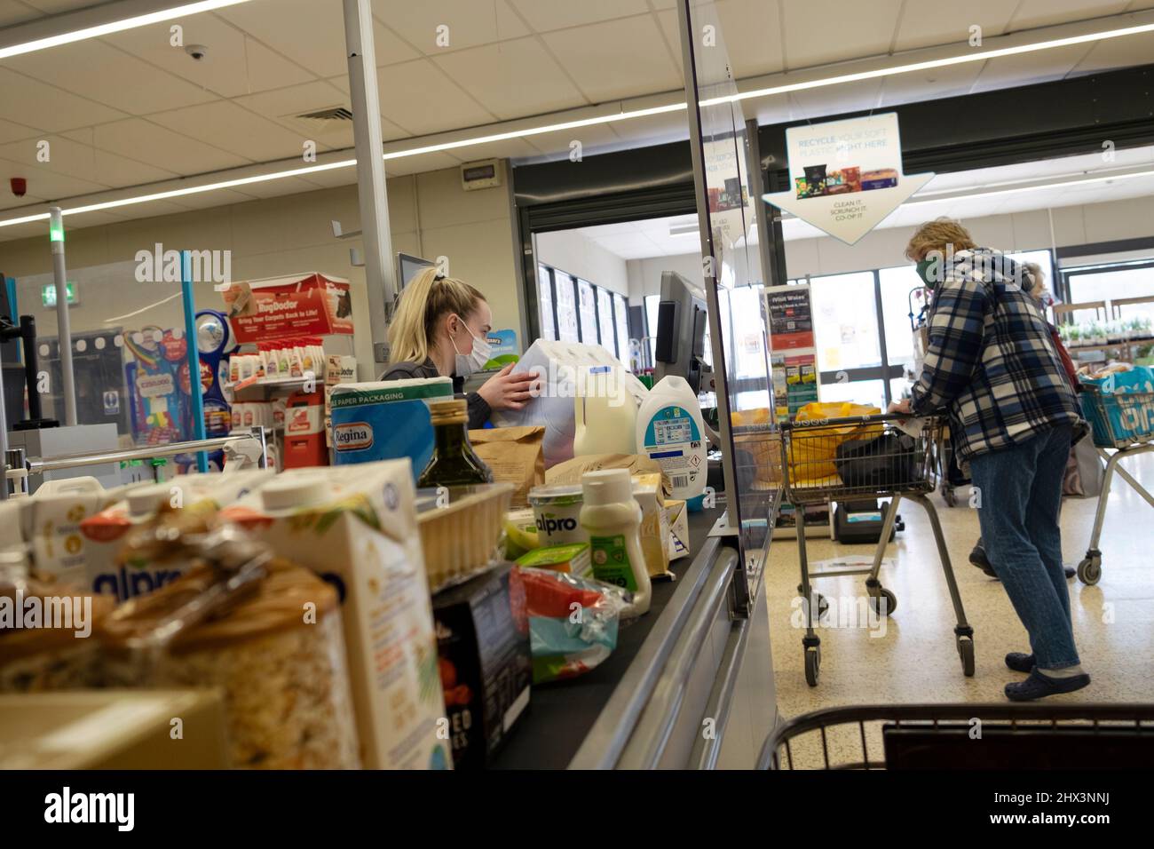 Lebenshaltungskosten Lebensmittel an der Kasse Co Op Supermarktarbeiterin Frau, die an der Kasse arbeitet und eine Covid-Maske trägt Wales 2022 KATHY DEWITT Stockfoto
