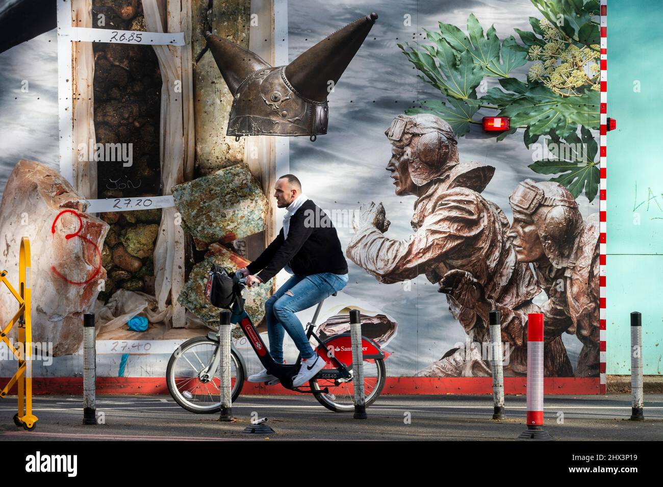 London, Großbritannien. 9. März 2022. Ein Radfahrer kommt an einem der zwei 25m langen Kunstwerke von Simon Roberts im Auftrag von Tideway vorbei, die „The Thames Wunderkammer: Tales from Victoria Embankment in Two Parts“ enthalten. Die Arbeit ist von Wahrzeichen und historischen Ereignissen inspiriert und befindet sich auf dem Bauzaun am Victoria Embankment, hinter dem Tideway den Thames Tideway Tunnel ausliefert, einen 25km-Kanal-Kanal-Kanal, der dringend benötigt wird, um die Abwasserverschmutzung in der Fluttfluß-Themse zu bekämpfen. Kredit: Stephen Chung / Alamy Live Nachrichten Stockfoto
