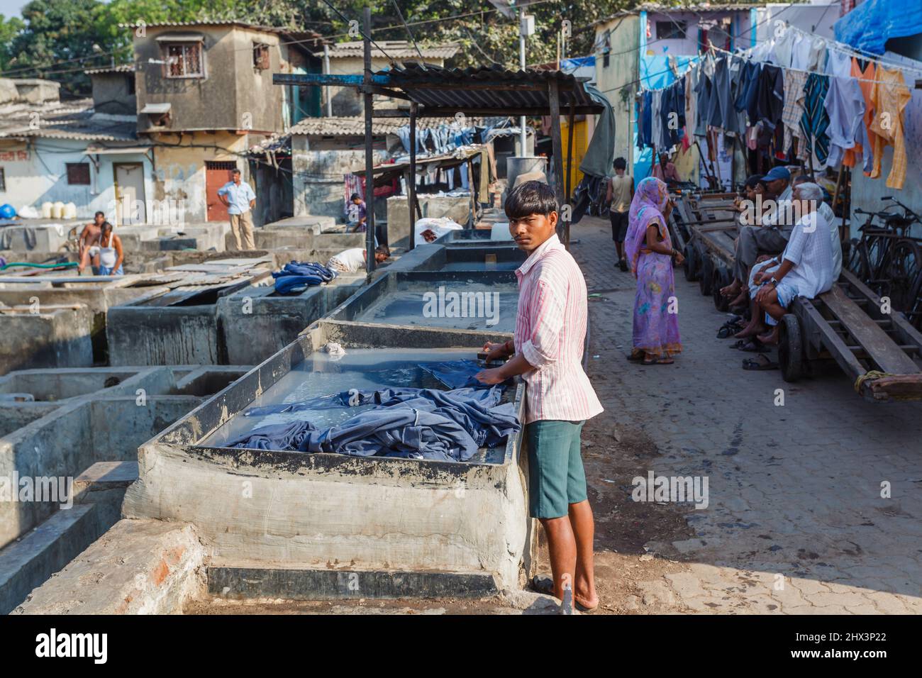 Ein Dhobi Wallah (Washerman) arbeitet Waschmittel in einem typischen Betonwaschstift in Mahalaxmi Dhobi Ghat, einem großen Open-Air-Waschsalon, Mumbai, Indien Stockfoto