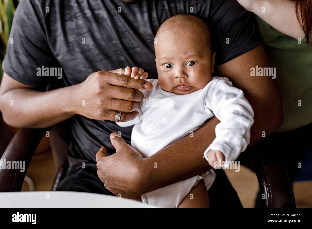 Glücklich afrikanischen jungen Vater sitzen mit kleinen Jungen Sohn Kind, verbringen Zeit mit jungen kaukasischen Frau, küssen Mann, gemischte Rasse Familie mit Kind zu Hause , Stockfoto