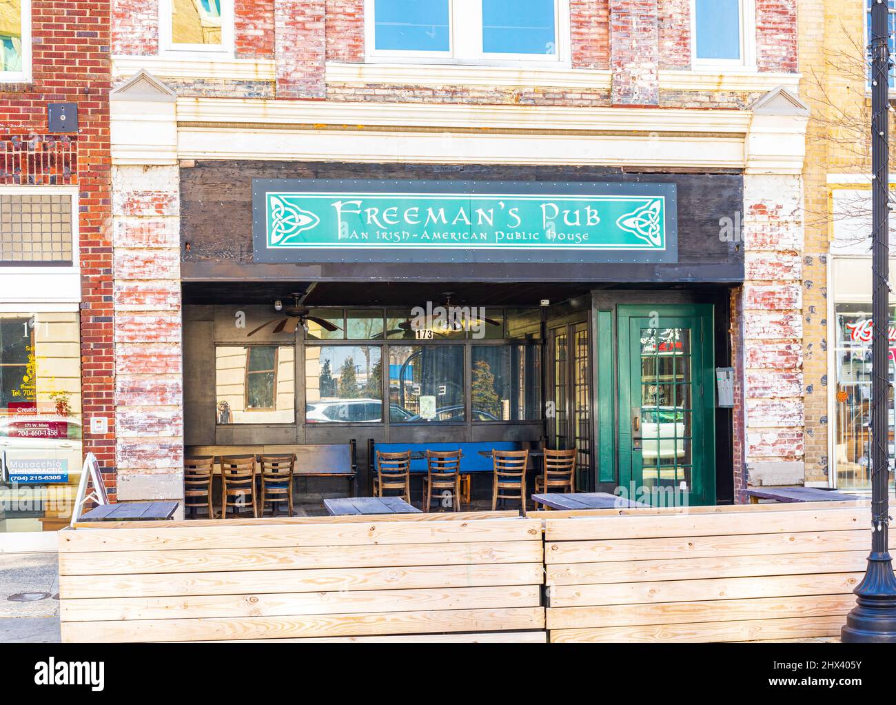 GASTONIA, NC, USA-3 MARCH 2022: Freeman's Pub, ein Irish-American Public House, zeigt Fassade, Eingang mit überdachten Sitzgelegenheiten im Freien und Grow-Boxen Stockfoto