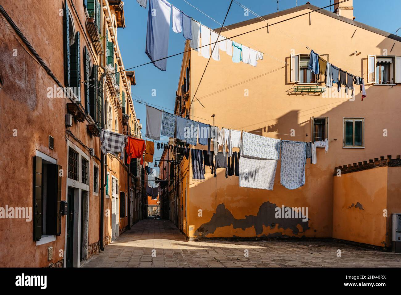 Wäsche hängt aus der typischen venezianischen Fassade, Italien. Enge Straße mit bunten Gebäuden und Kleidung trocken am Seil, Venedig. Saubere Kleidung trocknen im Freien Stockfoto