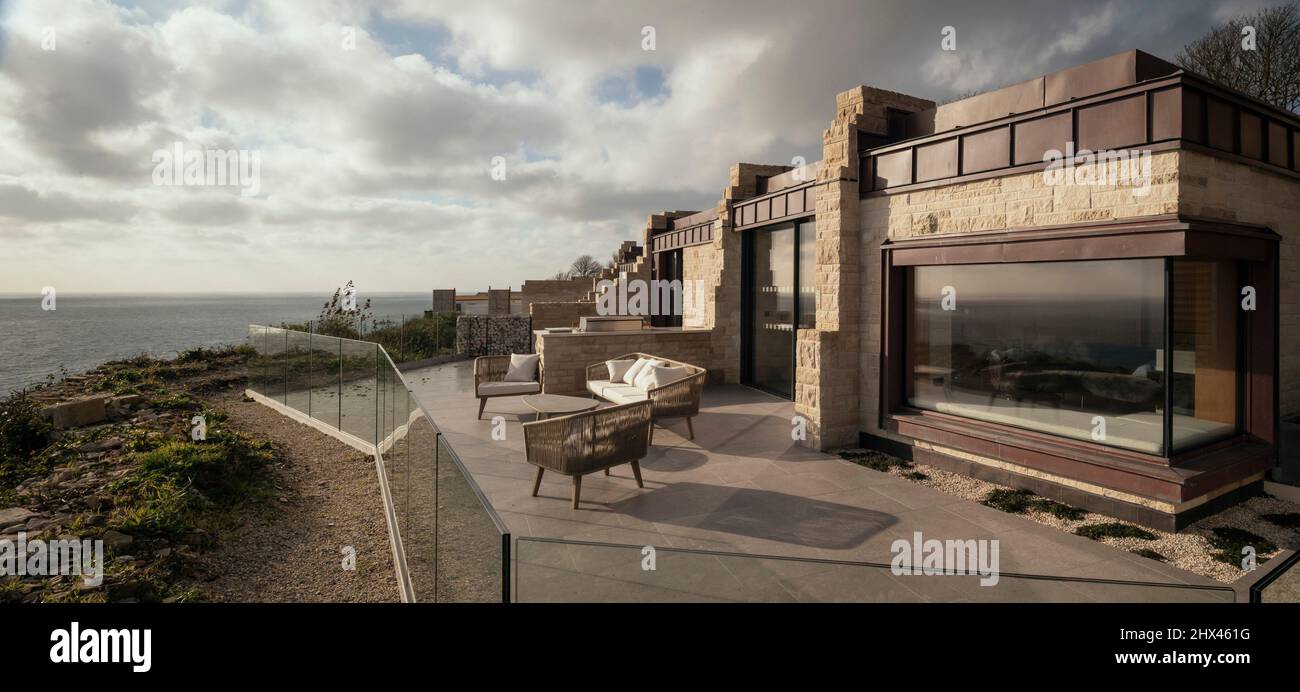 Außenansicht des Hotelunterkunftfensters mit privatem Sitzbereich, Außenküche, Aussichtsplattform, Meerblick und Fensterreflexionen von dramatischer Stockfoto