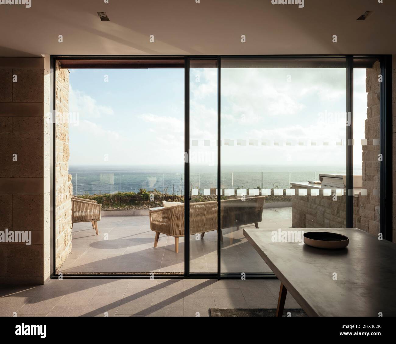 Blick nach innen auf große Schiebetüren auf die private Terrasse und Aussichtsplattform mit Sitzbereich. Clifftops, Dorset, Portland, Großbritannien. Lichtbogen Stockfoto