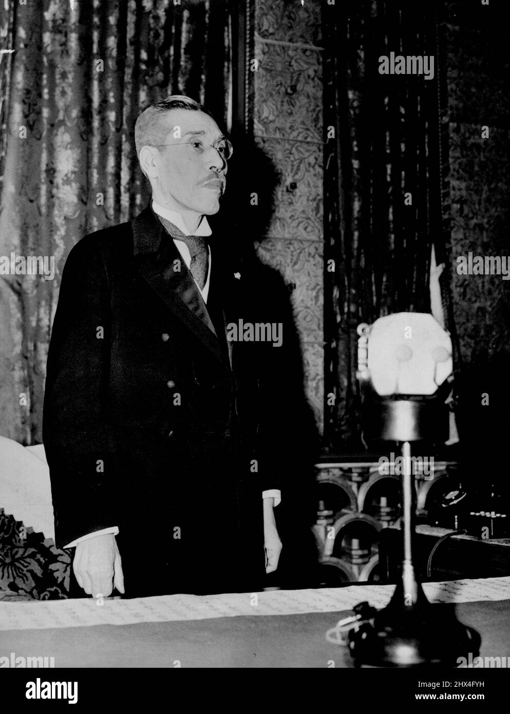 Neuer Premier Sendet Erste Botschaft An Die Nation -- Vor dem Mikrophon spricht hier, im offiziellen Wohnsitz des Premierministers, der 73-jährige Premierminister Kiichiro Hiranuma, der seine erste Sendung an die Nation sendet."Ich beabsichtige ausschließlich," sagte er, "das System der allgemeinen Mobilisierung der Nation zu intensivieren, um die Regierungspolitik für Innen- und Außenpolitik durchzusetzen." Dies zu stillen früheren Gerüchten über eine mögliche faschistische Tendenz: 'Ich werde jedoch keine der herkömmlichen Tracks betreten, noch etwas versuchen, das den Anschein hat, neu zu sein.' 7. Januar 1939. (Foto von Japan Photo Li Stockfoto