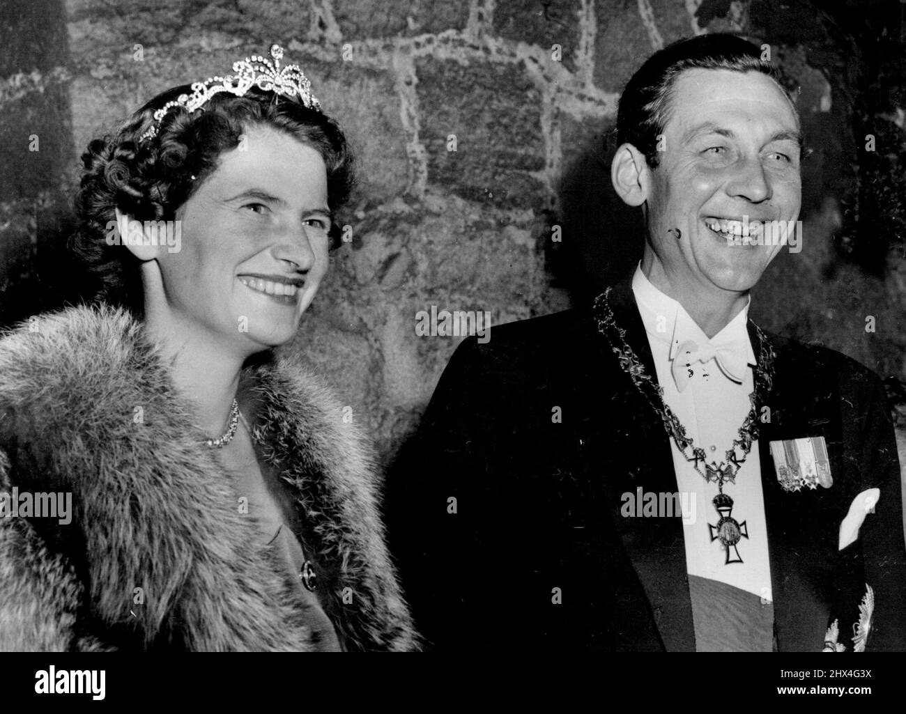 Königspaar sieht Fackelparade - Prinz Ernst August von Hannover und seine Braut, Prinzessin Ortrud zu Schleswig-Holstein Sonderburg Gluecksburg, stehen vor den Toren von Schloss Marienburg, als am Vorabend ihrer Kirchenhochzeit in Hannover rund 4.000 Wohlhabende eine Fackelparade zu ihren Ehren veranstalteten. Das Paar wurde letzte Woche bei einer standesamtlichen Zeremonie im Schloss verheiratet. 5. September 1951. Stockfoto