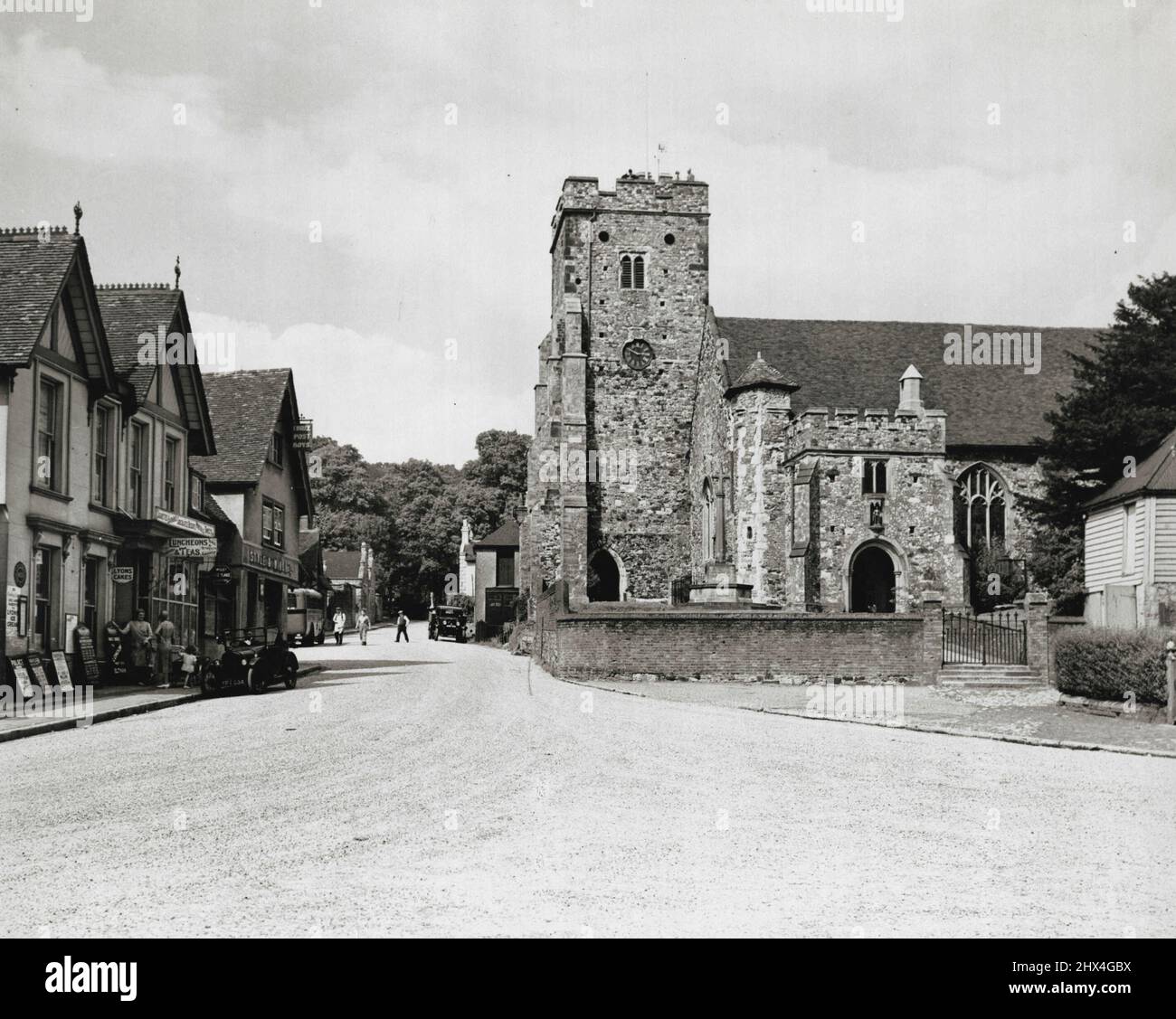 Ein umgehautes Dorf in Kent - kurz nachdem es den hohen Boden auf dem Wrotham Hill erreicht hat, wendet sich die Hauptstraße von London nach Maidstone Road nun nach Osten und vermeidet den steilen Abstieg nach Wrotham. So ist das alte Dorf, das sich unterhalb der Nort Downs schmiegt, ungestört von dem endlosen Verkehrsfluss, ungestört von dem endlosen Verkehrsfluss, der so nahe an ihm vorbeigeht. Die Überreste einer ehemaligen Residenz der Erzbischöfe von Canterbury befinden sich in der Nähe der stattlichen Pfarrkirche, die auf diesem Bild zu sehen ist, aufgenommen von einem Mitarbeiter Photographer of the Times. 9. Januar 1934. Stockfoto
