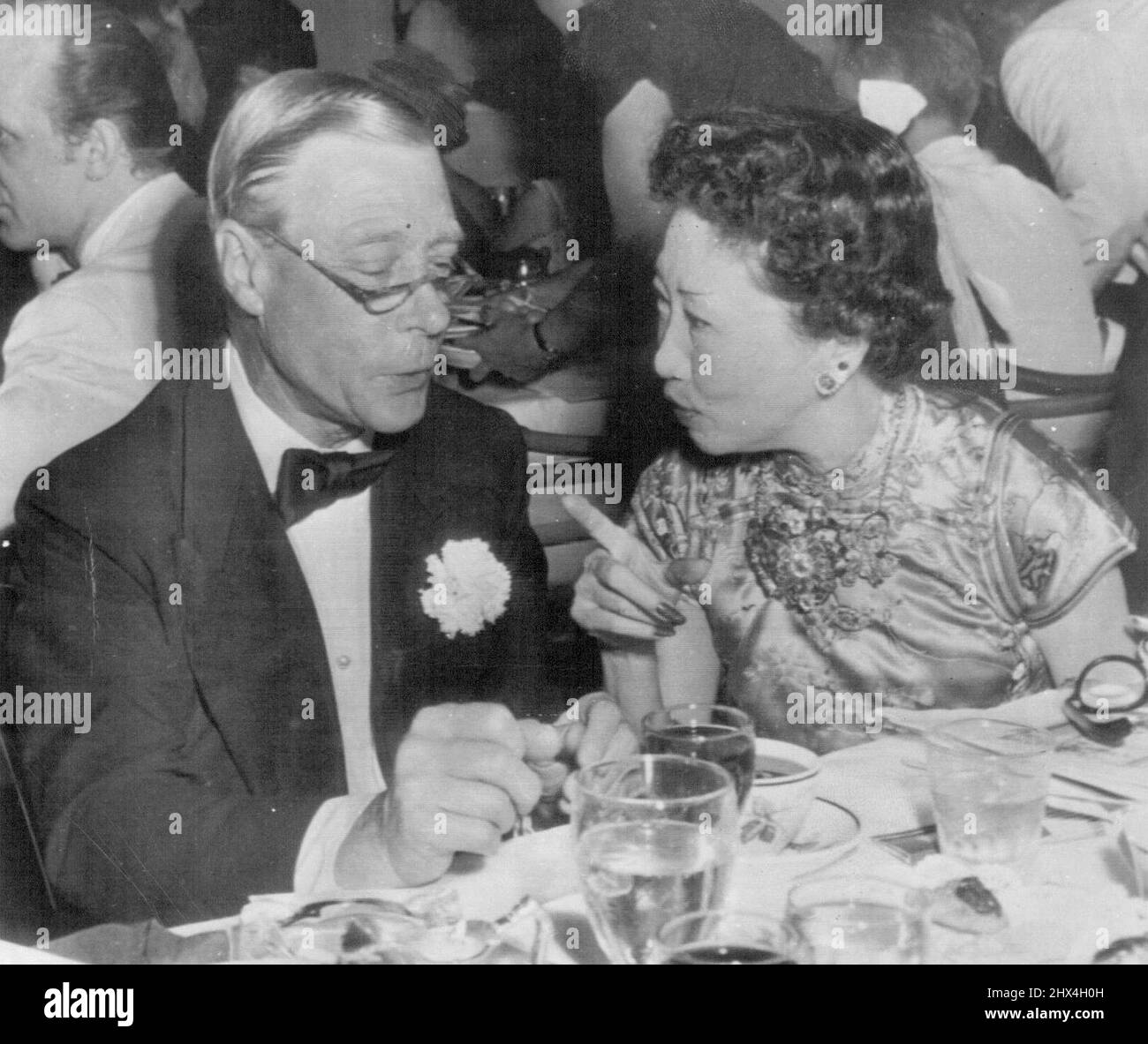 Jetzt hören Sie das -- der Herzog von Windsor, eine Brille hoch auf seiner Nase, hört, wie Madame Wellington Koo, Frau des chinesischen Botschafters in den Vereinigten Staaten, während sie gestern Abend mit ihm beim alljährlichen Wohltätigkeitsball im exklusiven Boca Ration Club hier spricht. Eine lange Liste von Notellen nahm an der Affäre Teil, die gehalten wurde, um Mittel für die Krebsforschung zu sammeln. 26. Februar 1955. (Foto von AP Wirephoto). Stockfoto