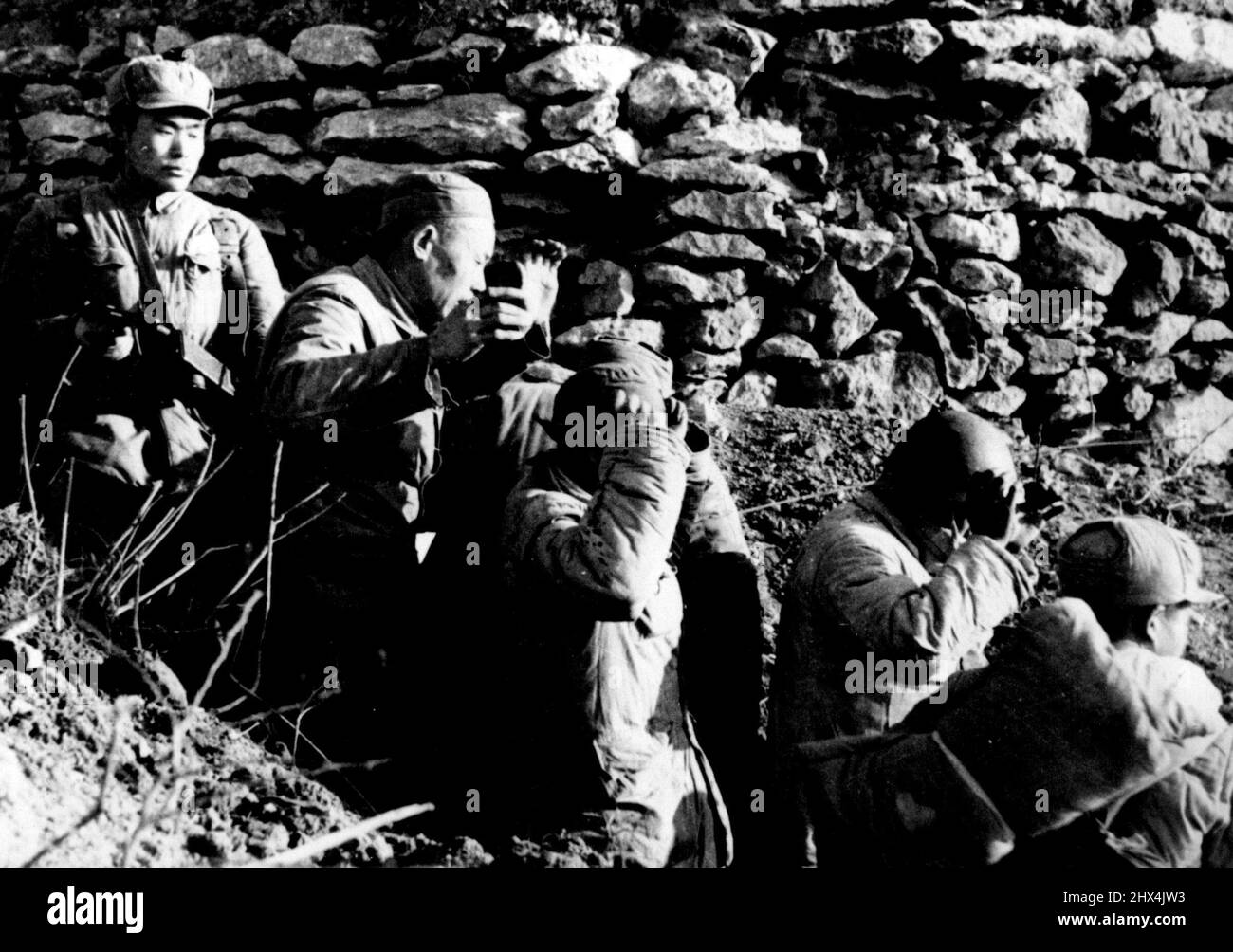 Gefangennahme von Yi Kiang Shan - die Truppen der chinesischen „Befreiungsarmee“ stürmten und eroberten die nationalistisch gehaltene Insel Yi Kiang Shan, eine der Tachen-Gruppe, am 18. Januar bei einem plötzlichen Angriff, der von Marine- und Luftstreitkräften unterstützt wurde. Laut kommunistischen Quellen in Peiping ließen diese nationalistischen Soldaten einen ihrer Bunker, nachdem die Insel kapituliert hatte. Ein chinesischer kommunistischer Soldat bedeckt sie mit der Pistole. 23. März 1955. Stockfoto