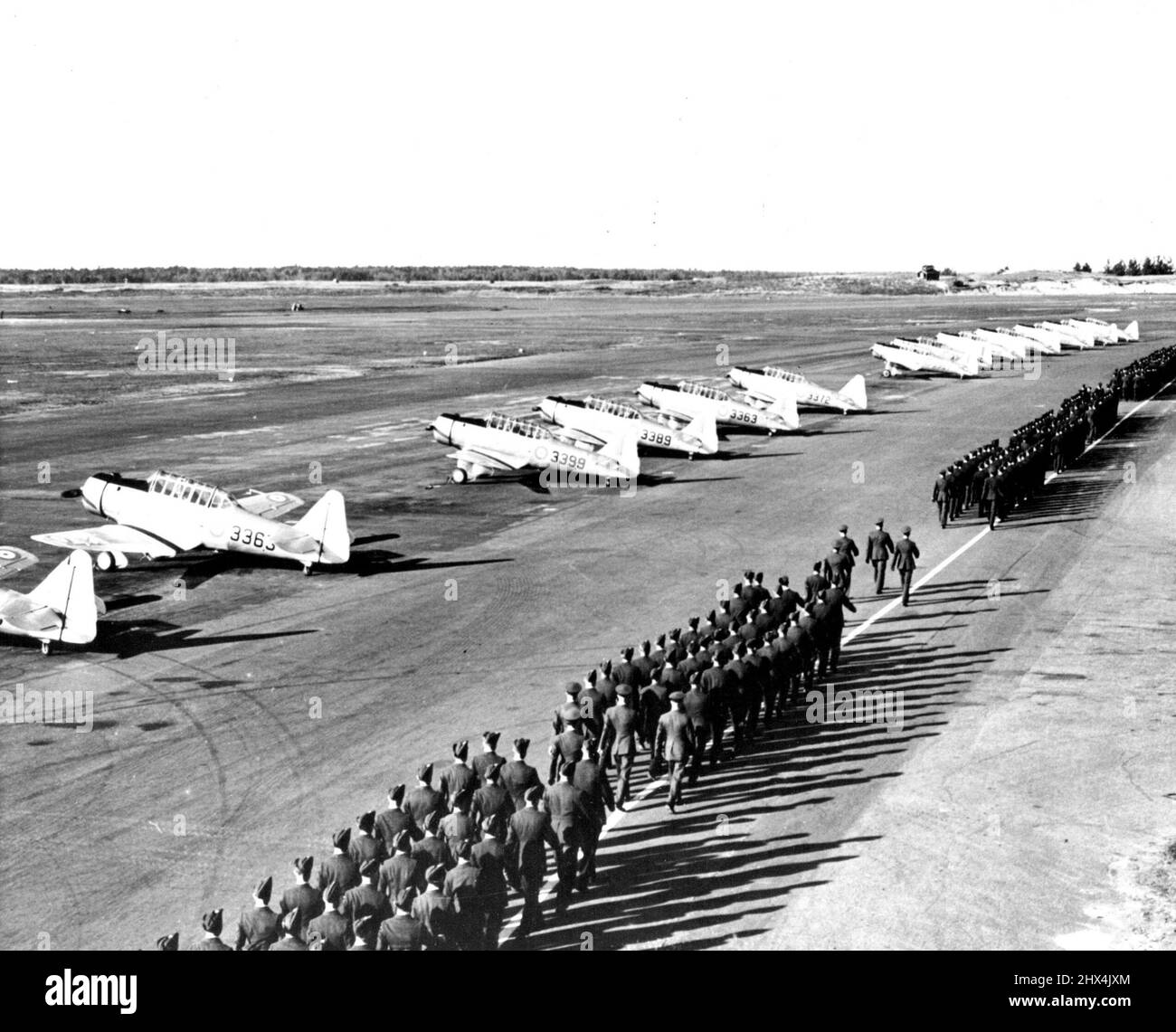 Mehr Canadian Airmen -- die Flieger der Royal Canadian Air Force im Camp Borden schwingen sich geschickt an einer Reihe von Yale-Trainingsflugzeugen vorbei, nachdem sie der ersten Gruppe von nicht-beauftragten Piloten im Training Flügel präsentiert haben. 10.Mai 1940. (Foto von ACME). Stockfoto