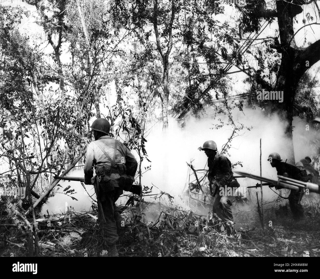 Yanks dringen im Rauchschirm vor Soldaten des Infanterie-Regiments 1., Division 6., dringen in die Cabaruan-Hügel, Insel Luzon, vor, nachdem sie mehrere Rauchgranaten vor sich geworfen haben. 19. Februar 1945. (Foto von USA Signal Corps). Stockfoto