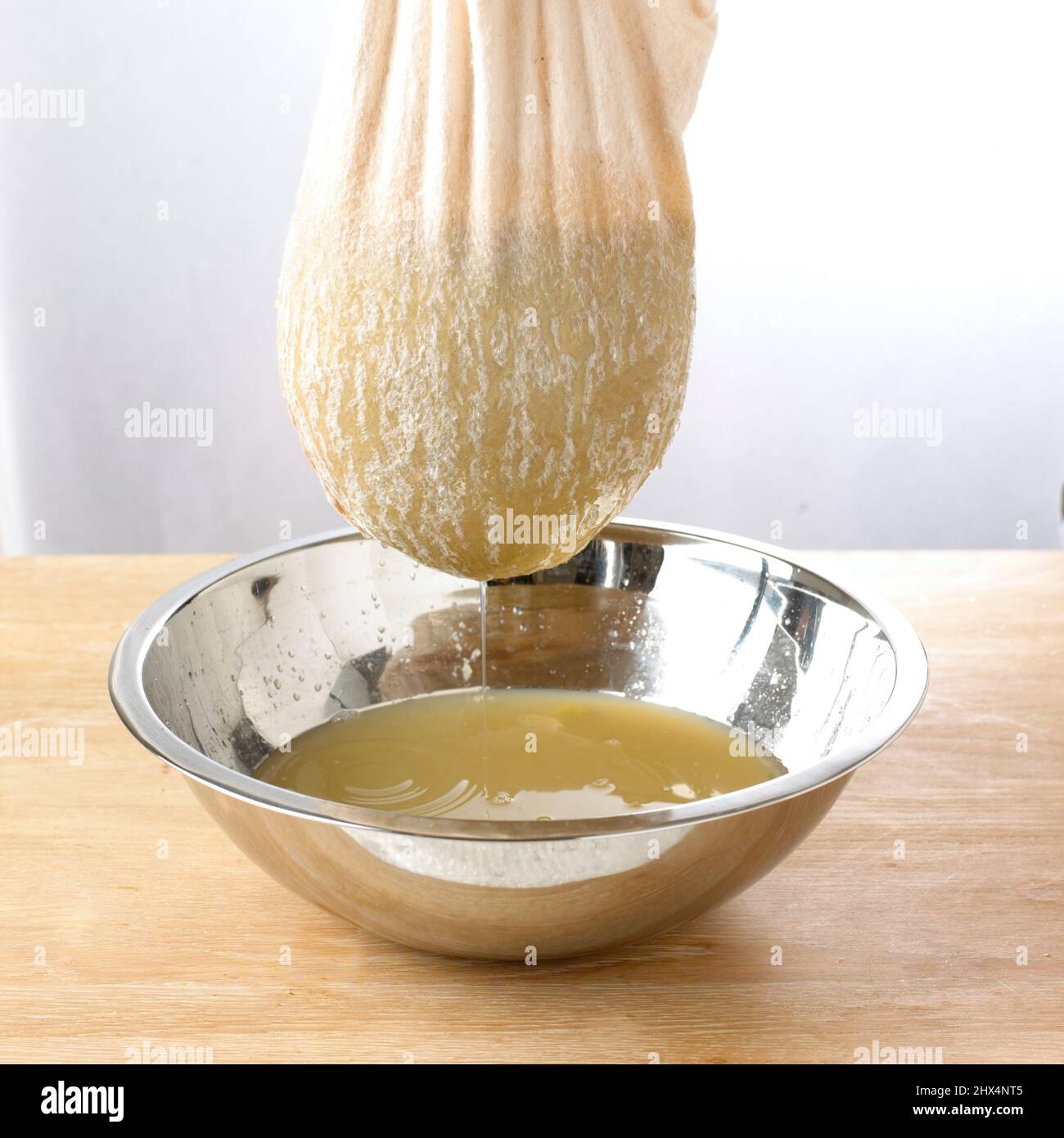 Die Traubenmischung durch ein Musselintuch in eine silberne Schüssel abseihen. Stockfoto