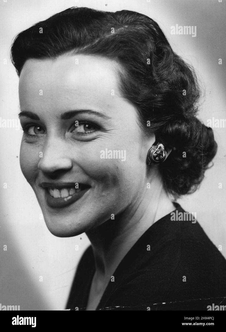 Der Ohrring verbirgt ein Hörgerät in diesem amerikanischen Gerät. Der kleine Empfangsbereich der Hilfe befindet sich im Ohrring. Ein transparentes Rohr verbindet es mit dem Set, das in der Tasche des Mantels oder Kleides verborgen ist. 30. September 1952. Stockfoto