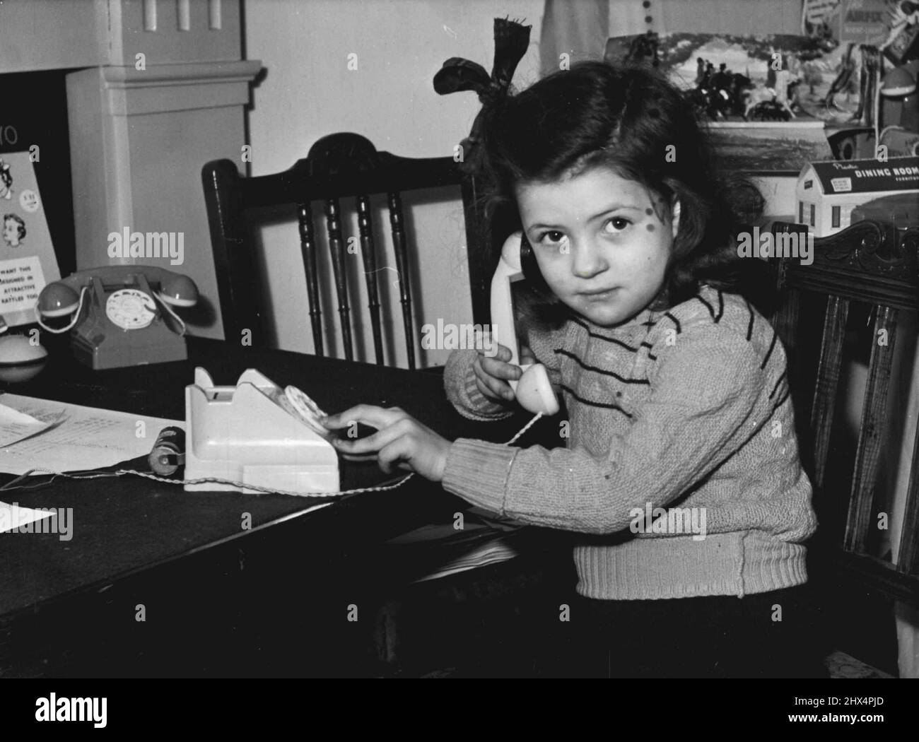 Wählen Sie B.B.C. -- das Telefon, mit dem das kleine Mädchen spielt, sieht aus wie ein Spielzeug. Tatsächlich handelt es sich um ein Funkgerät. Das Set war gestern auf der British Toy Fair in Harrogate, Yorks, zu sehen und wird in Kürze für £3 in den Geschäften verkauft werden. 15s. Sie wählen den Sender. 01. Januar 1951. Stockfoto