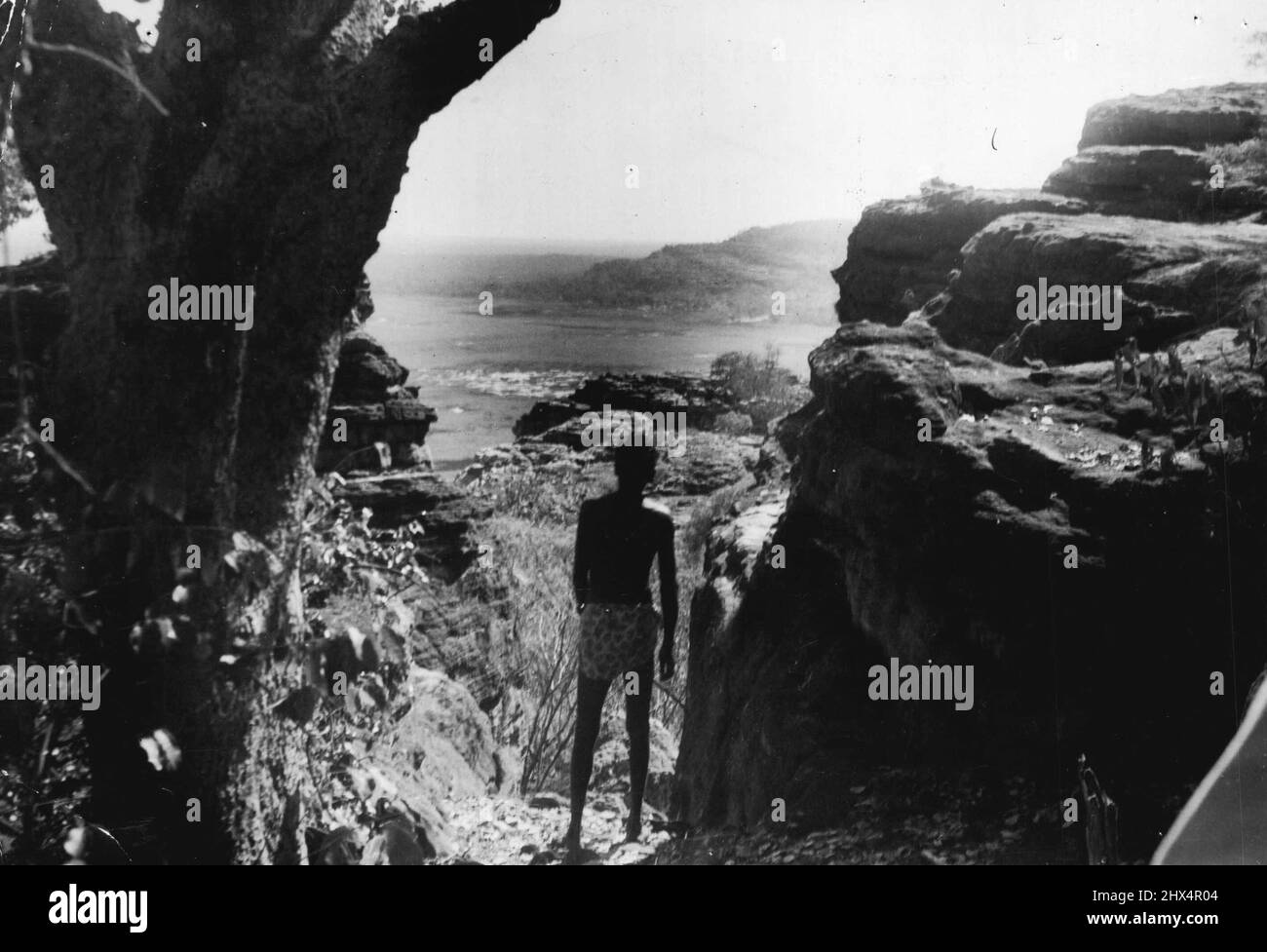 Maroowana untersucht sein Stammesland aus den Felsunterkünften in der Nähe von Oenpeli, wo der Stamm jede Regenzeit vorhergeht. Das Northern Territory (ein Einheimischer starrt oben auf sein „Walkabout“-Land). 6. Juni 1952. (Foto von Worrell). Stockfoto