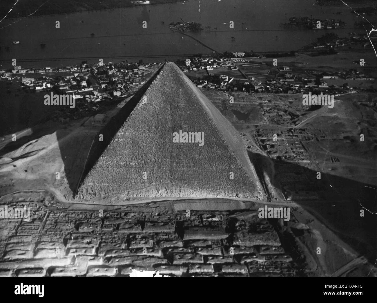 Große Pyramide Cheops und Dorf. Die große Pyramide von Cheops, in Gizeh, in der Nähe von Kairo. Pharaonen sahen sie nie so. Obwohl das Fliegen angeblich von den alten Ägyptern erfunden worden sein sollte, gibt es keine Aufzeichnungen über jeden Versuch der Luftfahrt. Luftaufnahme der Großen Cheops-Pyramide zeigen Schatten der zweiten Pyramide rechts und Ausgrabungen, die seit vielen Jahren im Gange sind. 15. Oktober 1955. (Foto der Luftwaffe der ägyptischen Armee). Stockfoto