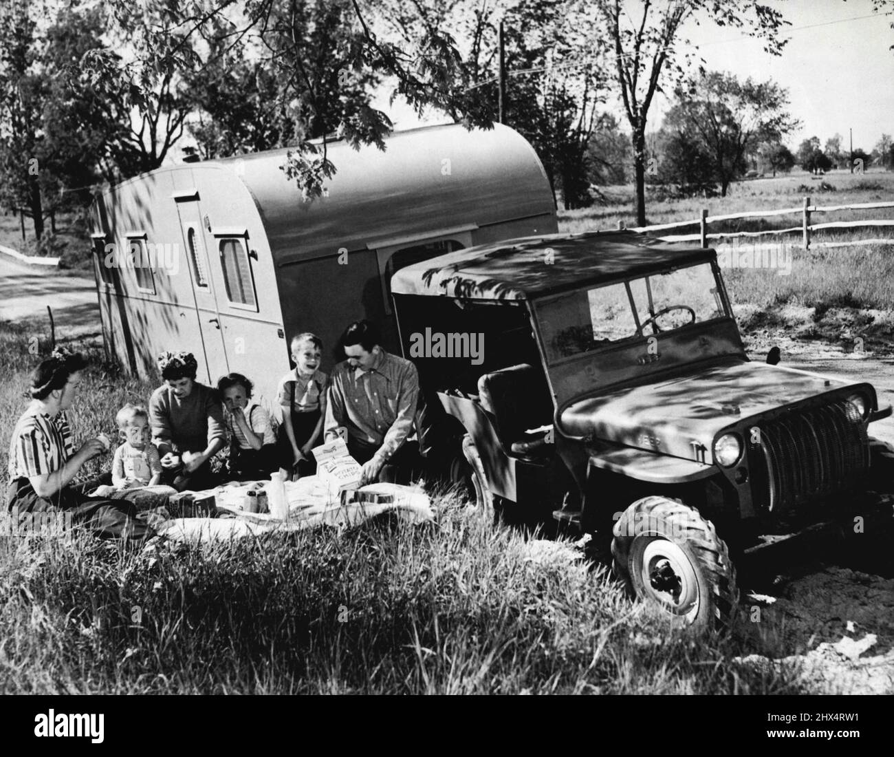 Jeep-of-All-Trades -- Touring...als Anhänger-Schlepper hat der Jeep keinen Peer. Dieses hat seine Oberseite oben, um Papa etwas von dem Komfort zu geben, den Mutter und die Kinder im luxuriösen Anhänger genießen. Der zivilvative Jeep ist in schwulen Farben lackiert, was ihn attraktiver zu betrachten macht als der Militärbruder in seinem olivgrünen Mantel. 16. September 1945. (Foto von C.J. Nichols, Internationale Nachrichtenfotos). Stockfoto