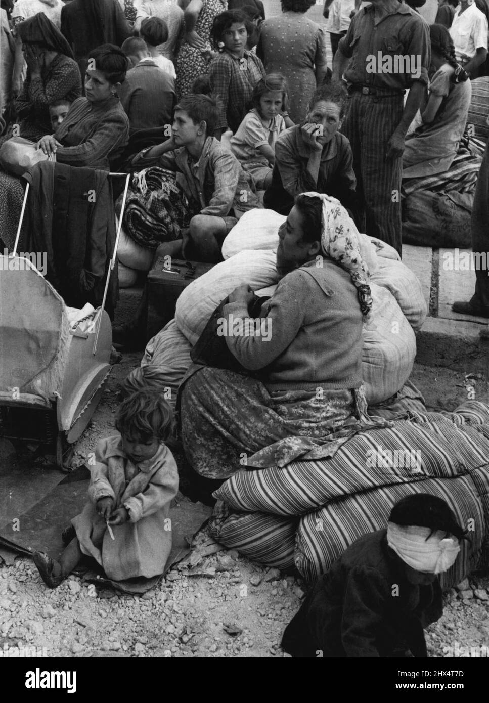 Ein verbandtes, verletztes Kind spielt in den Trümmern, während Mutter und andere warten, in der Hoffnung, dass sie von der Insel gebracht werden. 17. August 1953. (Foto von Daily Mirror). Stockfoto