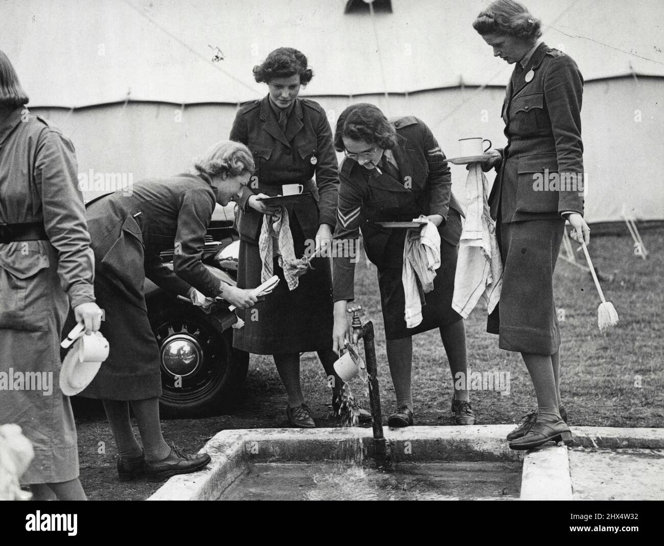 Nur Frauen-Transport-Korps im Lager - Abwaschen! Jeder Camper muss nach dem Essen im Gemeinschaftswaschbecken seine eigenen „Krocks“ abwaschen. Mitglieder des einzigen Frauentransportkorps, das seit dem Krieg ohne Unterlass seine Ausbildung und Rekrutierung fortgesetzt hat, sind jetzt im Lager in Mychett, in der Nähe von Aldershot, Hampshire. Sie gehören dem Frauenverkehrsdienst an, der vom Armeerat als freiwillige Transportorganisation anerkannt wird. In Zeiten nationaler Notlage steht das Korps der Regierung zur Verfügung. In Friedenszeiten geben Mitglieder den Krankenhäusern wertvolle Hilfe durch ein regelmäßiges Transportprogramm für Pati Stockfoto