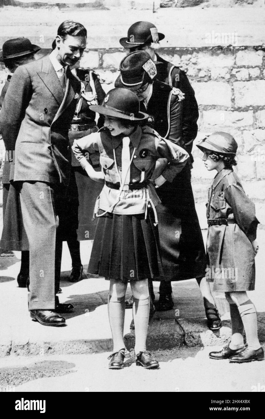 Inspektion von Mädchen-Guides in Windsor Ein charmanter Vorfall während der Märzvergangenheit der Mädchen-Guides. Unser Foto zeigt Prinzessin Elizabeth, die den Gürtel ihrer Uniform justiert hat. Seine Majestät König George VI schaut auf. Prinzessin Margaret ist rechts in der Brownie-Uniform zu sehen. Dies ist das erste Mal, dass die Prinzessinnen eine Veranstaltung in ihrer Girl Guides Uniform besucht haben. 11. Juli 1938. Stockfoto