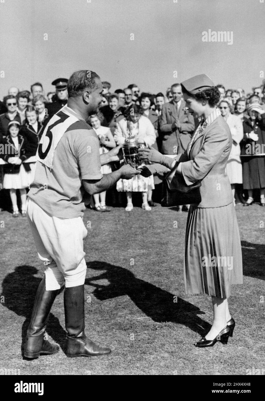 Royal Family Finale der Windsor Polo Week. H. M., die Königin, hat Rao Rajah Ranut Singh, dessen Team Ratanada heute Nachmittag im Finale Ham schlug, den Royal Windsor Cup vorgestellt. In Windsor wurden heute die letzten Spiele des Household Brigade Ascot Week Polo Tournament ausgetragen. Mitglieder der königlichen Familie, die die ganze Woche über begeisterte Zuschauer bei den Spielen waren, schauten sich heute erneut zu, und zur Königlichen Partei gehörten König Hussein und Königin Dina von Jordanien, die dieses Land besuchen. 18. Juni 1955. (Foto von Fox Photos). Stockfoto