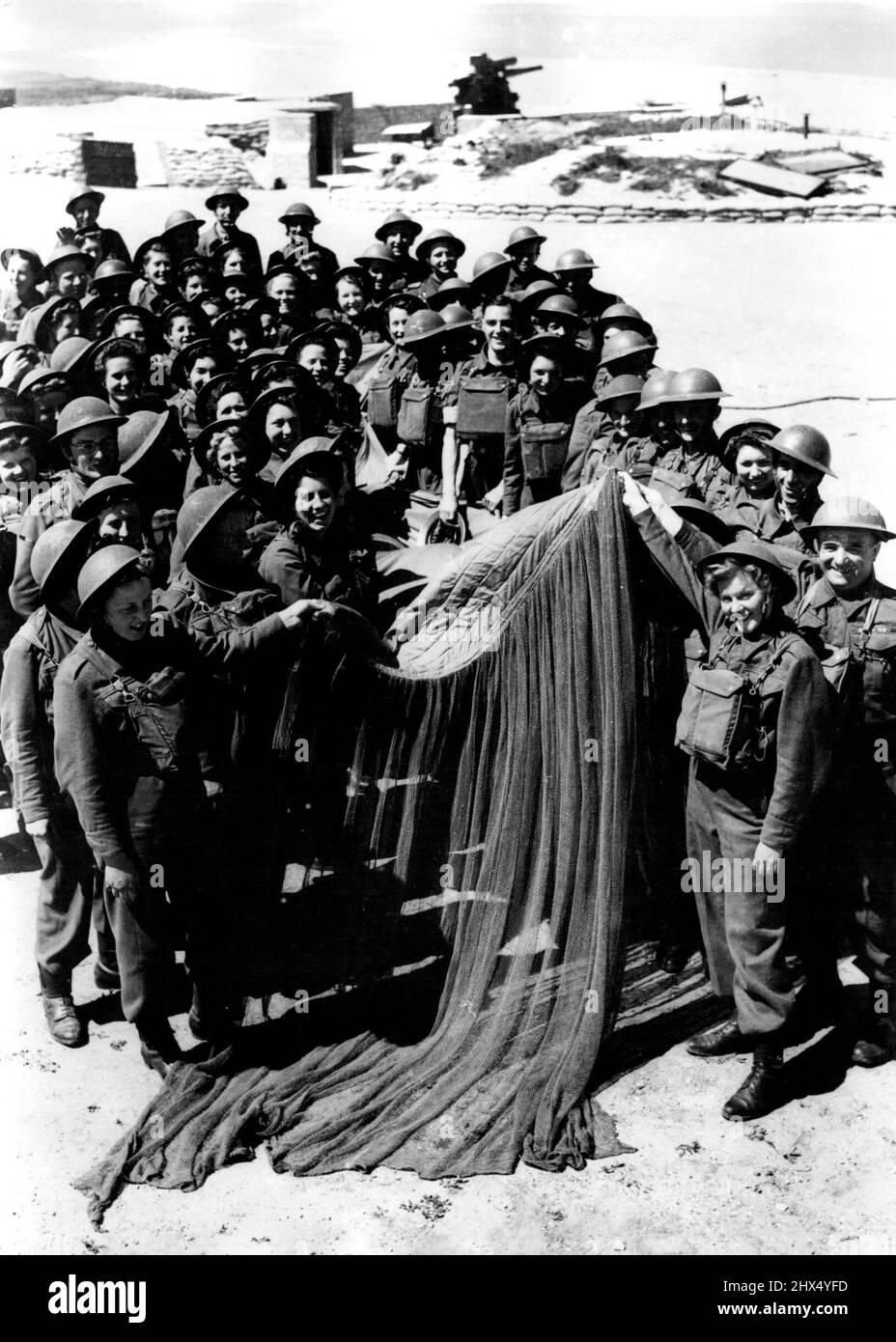 Übungslager für A.A. Mädchen - Männer und Mädchen von A. Befehl mit dem beschädigten „Leeve“, den sie erfolgreich heruntergebracht haben. Einige der Mädchen, die sich für die A.A-Niederlassung der A.T.S. entschieden haben, werden in einem gemischten schweren Anti-Aircraft-Übungslager in East Anglia ausgebildet. Ihre Aufgaben sind es, sich nähernde feindliche Flugzeuge zu erkennen und die Höhe und Reichweite des Ziels zu finden. Zu diesem Zweck werden sie geschult, mit Hilfe von Flugzeugen, die „Sleeve“-Ziele schleppen, genau zu sein, und die hervorragende Leistung, die sie aufgelegt haben, hat der von Männern, die die gleiche Arbeit tun, gleichgesetzt. June25, 1942. (Foto von FOX Photos). Stockfoto