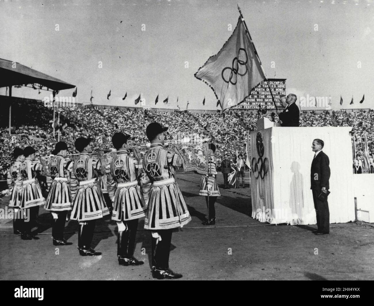 Abschluss der Spiele der XIV. Olympiade : auf der Tribune of Honor (nächste Kamera) stehend hält Sir Frederick Wells, Oberbürgermeister von London, die olympische Flagge, die bis zur XV. Olympiade, die in Helsinki gefeiert werden soll, in seiner sicheren Aufbewahrung bleiben wird. Auf diesem Bild, das während des Abschlusses der Spiele der XIV. Olympiade im Wembley Stadium, London, im August 14., gemacht wurde, sind auch J. Sigfrid Edstrom, Präsident des Internationalen Olympischen Komitees (auf Tribüne am weitesten von der Kamera entfernt), und rechts im Vordergrund steht Lord Burghley, Vorsitzender des Organisationskomitees. Auf der linken Seite befinden sich State Trumpe Stockfoto