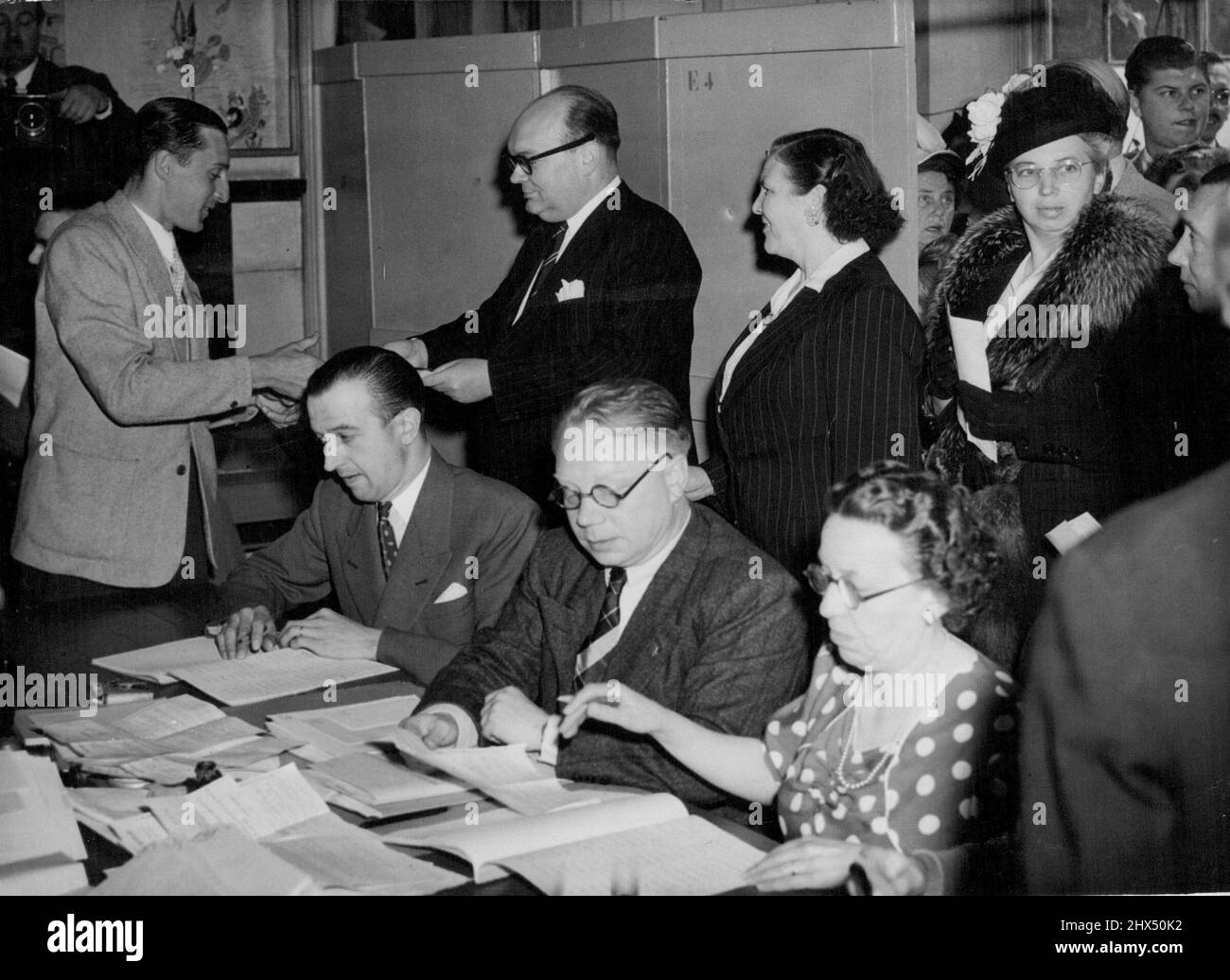 Spaak stimmt bei den belgischen Wahlen ab -- Herr Paul Heri Spaak, belgischer Premierminister und Außenminister, sammelt seine Stimmzettel, um seine Stimme in Brüssel für die Parlamentswahlen am heutigen 26. Juni abzugeben. Mit ihm sind einige belgische Frauen, die bei den Wahlen zum ersten Mal gewählt haben. 15. Juli 1949. Stockfoto