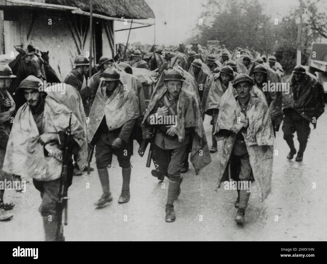 Jugo-slawische Truppen an der ungarischen jugo-slawischen Grenze Eine Abteilung jugo-slawischer Infanterie fotografiert, als sie durch ein Dorf in Richtung der Grenze zwischen Jugo-Slavia und Ungarn marschieren. Sie verwenden Mackintosh-Kapes, um sie dann vor dem Regen zu schützen, während sie gehen. Wie andere europäische Länder hält auch Jugo-Slavia alle ihre Grenzen gut besetzt, trotz der Proteste ihrer Nachbarn, dass sie nichts als Frieden wollen. 24. April 1939. (Foto von Keystone). Stockfoto