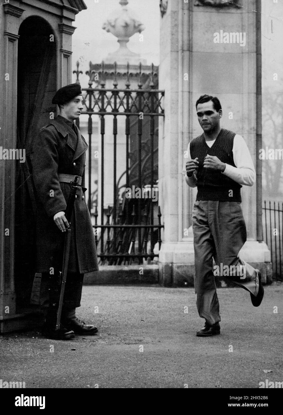 Sightseeing zu Fuß -- der Australier Dave Sands, Middle Associated Press Photoweight, Champion im Schwergewicht und Schwergewicht, kombiniert Straßenarbeit mit Sightseeing, während er heute, March22, am Wachposten im Buckingham Palace vorbeijoggt. Der 23-jährige Champion mit dunkler Haut, der in Großbritannien auf der Spur der Welthulden ist, wird am 4. April erstmals in Harringay mit dem amerikanischen Leichtblattwight Tommy Yarosz verglichen. 22. März 1949. (Foto von Associated Press Photo). Stockfoto