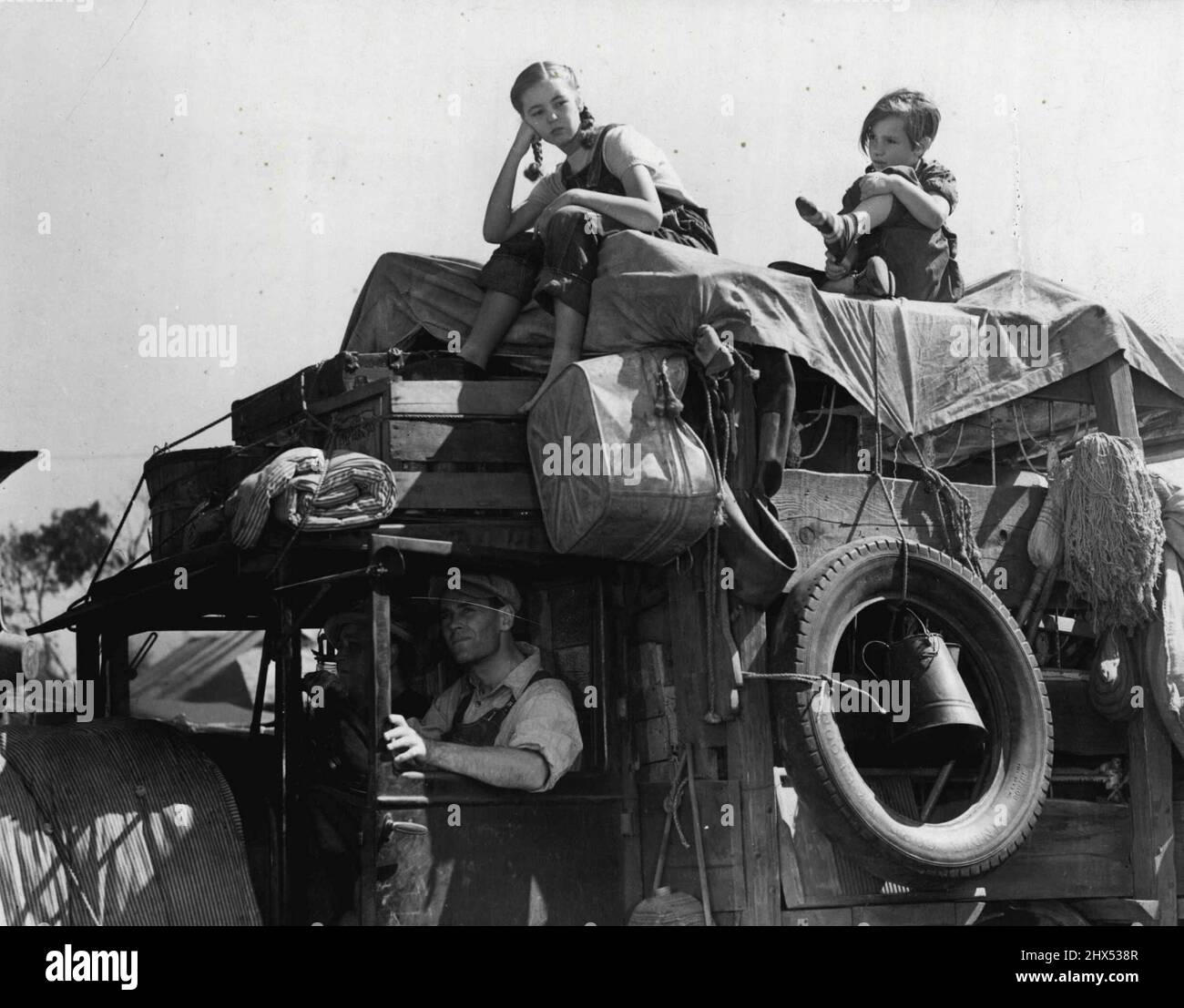 Hollywood Gal. - Die Verfilmung von John Steinbecks Roman, 'The Grades of Wrath', wird bald von 20. Century Fox veröffentlicht. Diese Geschichte zeigt die Notlage einer Familie aus Oklahoma, die „Dust Bowl“, auf der Suche nach Arbeit und guten Lebensbedingungen, aber mit wenig oder gar keinem Erfolg nach Kalifornien auswanderte. In dieser Szene aus dem Bild sind einige der Joads in dem heruntergefahrenen Fahrzeug zu sehen, das sie und ihre Besitztümer nach Westen trug. Henry Fonda als Lom Joad fährt: Neben ihm sitzen Jane Darwell und Ma Joad. Shirley Mills und Darryl Hickman sind oben auf dem Truck. 'Die Trauben des Zorns,' Stockfoto