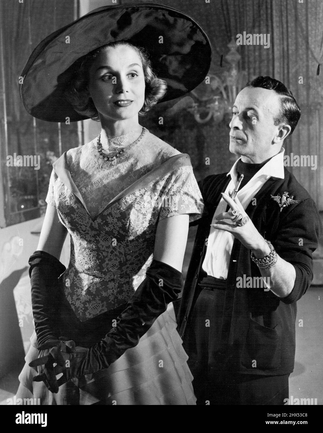 Spotlight on Skirt (First of Seven) -- Vorbereitung eines seiner Frühjahrs-Modell ***** Zeigen, Rom Stylistin Emilio Schubert ***** Letzter Check-over mit einem Indigo Blue-Organgandy Nachmittagskleid. Diagonale Falten bedecken den gesamten Rock und chantilly Spitze schmückt das Mieder. Die Halslinie ist ideal für Schmuck, den Schubert sehr liebt, als Zeuge der Armvoll von goldenen Armbändern und Diamanten, die er immer trägt. Obwohl er Italiens anerkannter Modeführer ist, wurde der Künstler mit den Armreifen, den Ringen und den langen, spitzen Nägeln in Deutschland geboren. 25. Januar 1952. (Foto von United Press - ACME). Stockfoto