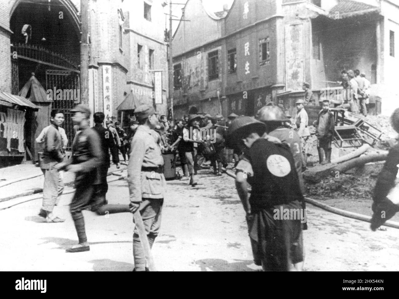 Ein A mein Beamter und Zuschauer tauchen aus Verstecken auf, um die Verwüstung dessen zu betrachten, was angeblich eine Militärstruktur in Chungking war, die während des schweren japanischen Marineangriffs auf die chinesische Hauptstadt am 4. Mai geebnet wurde. Dieses Foto, aufgenommen von einem Ausländer, wurde mit dem Boot nach Hongkong, nach Shanghai geflogen und dann hierher geflogen. 15.Mai 1939. (Foto vom Domei News Photos Service). Stockfoto