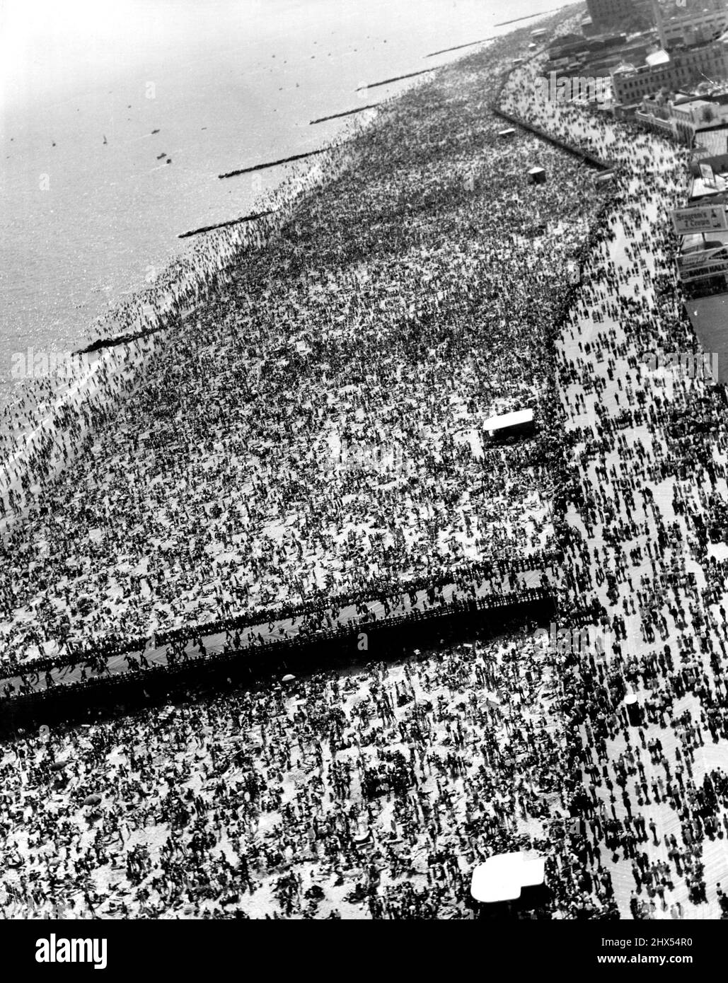 Coney Island - New Yorks fabelhafter Spielplatz -- Coney Island, mit seinen Sandstränden und Vergnügungsparks, ist nur 14 km mit der U-Bahn vom Herzen von New York entfernt und hat ausnahmslos einen überfüllten Look. Wie seine Pendants in anderen Ländern wirkt sie als Magnet für die Tausenden von Menschen, die die meiste Zeit ihrer Tage in der Großstadt leben und arbeiten. Es wurde geschätzt, dass an Feiertagen und an Wochenenden über 200.000 Menschen an den 4½ Meilen Strand strömen. Im Hochsommer schwebt die Temperatur um die 100-Grad-Marke, und die Promenaden werden dann mit Menschen gefüllt, die die Hitze auf dem nicht aushalten können Stockfoto