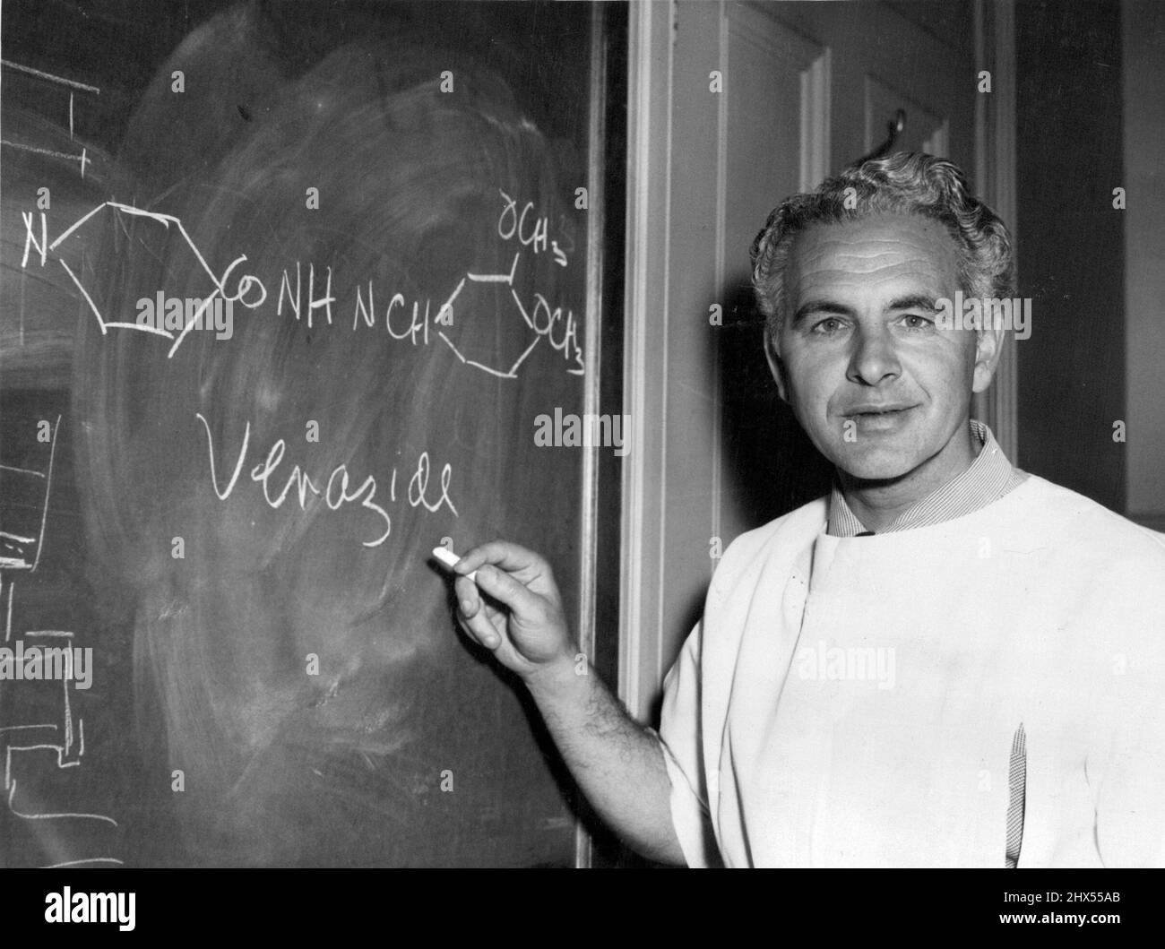 Dr. Rubbo zeigt auf der Tafel die Formel und den Namen des neuen TB-Medikaments. Das neue Tuberkulosebekämpfungsmittel Verazid wird wahrscheinlich zuerst bei den Neuguinea-Ureinwohnern eingesetzt. Das hat heute der Professor für Bakteriologie an der Universität Melbourne, Dr. Sydney Rubbo, der das Medikament zusammen mit dem Senior Lecturer in Organic Chemistry an der Universität Sydney, Dr. J. Cymerman-Craig, entwickelt hat, enthüllt. Die Droge ist harmlos und wird in Neuguinea zuerst wegen der hohen Inzidenz von TB unter den Einheimischen dort versucht werden. 17. November 1955. (Foto von The Herald & Weekly Times Ltd.). Stockfoto