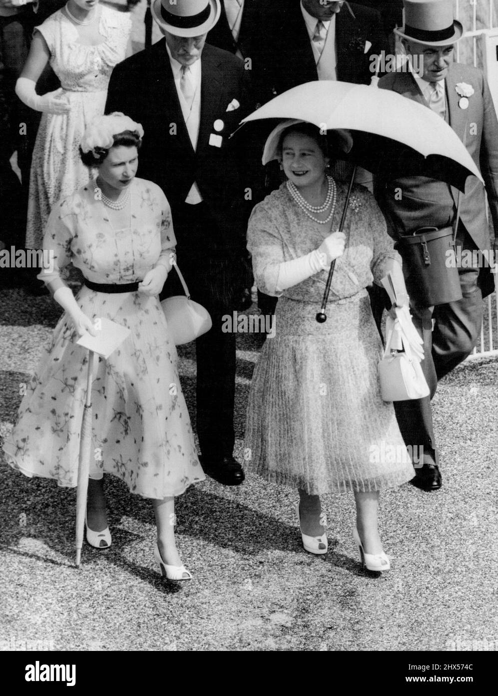 Royal Dresses Match the Sun - die Queen Mother hebt ihren Sonnenschirm gegen die pralle Sonne, aber der Sonnenschirm der Queen ist gerellt, als sie zum Fahrerlager gehen, um die Goldcup-Läufer beim königlichen Ascot-Renntreffen heute (Mittwoch) zu sehen. Das weiße Seidenkleid der Königin wird von einem weißen Blütenblatthut gekrönt. Das Kleid ihrer Mutter ist in hellem Hyazinthblau gehalten, getragen mit einem großen Hut aus blauem und weißem Organdie. 13. Juli 1955. (Foto von Reuter Photo). Stockfoto