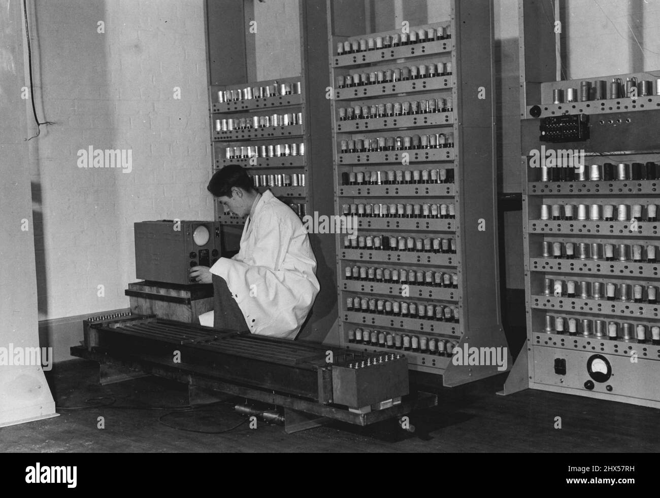 Die „Memory“-Einheit des Electronic Delay Storage Calculators wird jetzt am Mathematical Laboratory der Universität Cambridge verwendet. Das Gerät ist vollständig und wird als lange Röhrenbatterie vor dem Bediener gesehen. Jedes Rohr wird mit Quecksilber gefüllt und an jedem Ende mit einem Quarzkristall gestoppt. Impulse werden beim Eintritt in die Rohre in Überschallschwingungen im Quarz umgewandelt. Der Quarzkristall am fernen Ende wandelt sie wieder in elektronische Impulse um, die gesammelt, verstärkt und „gereinigt“ werden und in die Röhren zurückgeleitet werden. Der Calcualtor selbst hat über 3.000 Ventile. 01. April 1950. Stockfoto