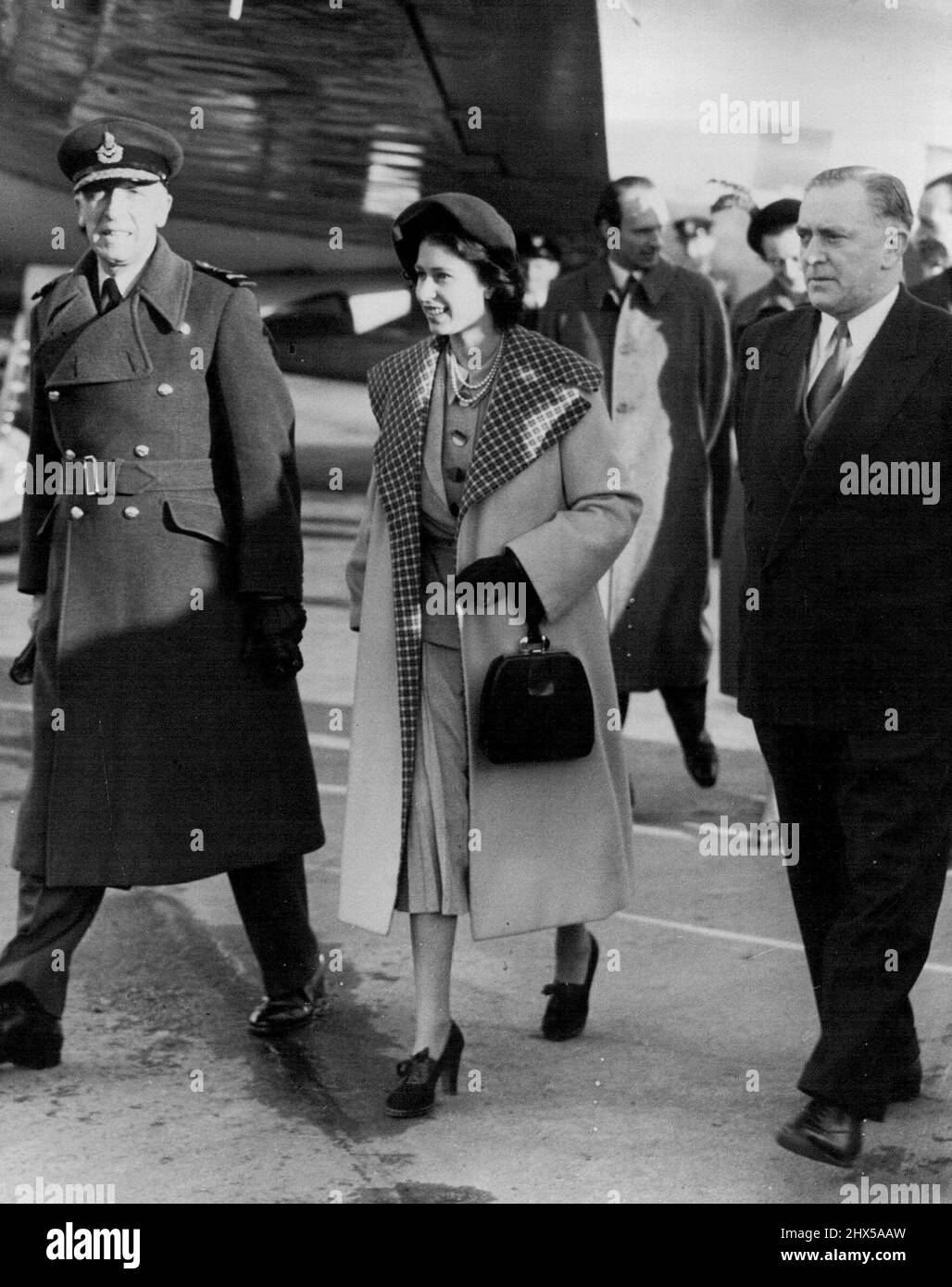 Prinzessin Elizabeth Home from Malta - Home from Malta in a Viking Aircraft of the King's Flight - spaziert auf dem Asphalt, der heute (Montag) in strahlendem Sonnenschein gebadet wurde, nachdem er am Flughafen London landete. Sie war mit ihrem Mann, dem Herzog von Edinburgh, auf Malta gewesen, und die Prinzessin trägt einen kanariengelben Wendemantel mit einem großen Karokragen über einem grauen zweiteiligen Anzug. Sie trägt eine doppelte Perlenreihe, braune Schuhe und eine braune Handtasche. Der Rest der königlichen Familie, einschließlich der beiden Kinder Prinz Charles und Prinzessin Anne von Prinzessin Elizabeth, kam heute von Sandringham aus nach London. Februar Stockfoto