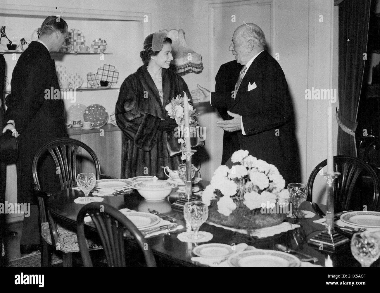 Königin beginnt Herr 3-County Tour of the Midlands -- die Königin lächelt ihr Dank, als sie von Sir Ernest Johnson, dem Vorsitzenden der Herren Johnson Bros. (Hanley) Ltd., einem bekannten Stoke-on-Trent Potteries, während ihres Besuchs dort heute Nachmittag mit S.R.H. dem Herzog von Edinburgh, einen schönen Dinner-Service erhalten wird, Wer kann im Hintergrund gesehen werden, indem er die Ausstellungsstücke untersucht. H. N. Die Queen und S.R.H. der Herzog von Edinburgh begannen heute ihre zweitägige Tour durch die Midlands, die sich in drei Grafschaften erstreckt. Während ihrer schweren 13-Stunden-Programm heute, sie besuchten Nantwich, Crewe, Newcastle-under-Lyme, Th Stockfoto