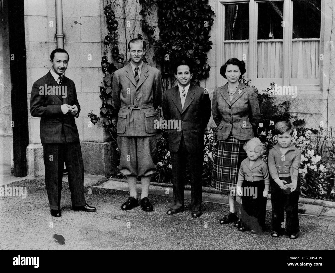 Die Königin mit ihren königlichen Besuchern im Balmoral - die Königin, die einen Tartanrock und eine Tweed-Jacke trägt, fotografiert vor dem Balmoral Castle mit ihrem königlichen Gast, König Faisal II. Vom Irak, dem Herzog von Edinburgh, Prinzessin Charles und Prinzessin Anne und, links, dem Regenten des Irak. Prinzessin Charles und Prinzessin Anne sind in langen Hosen und zweireihigen Strickjacken gemütlich warm, während ihr Vater eine Schießjacke und Viere bevorzugt. 26. September 1952. (Foto von Reuterphoto). Stockfoto